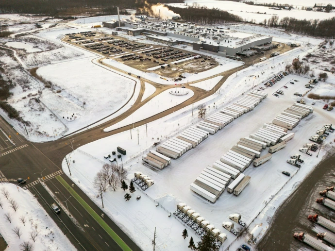 Aerial view of a snowy industrial complex with trucks.